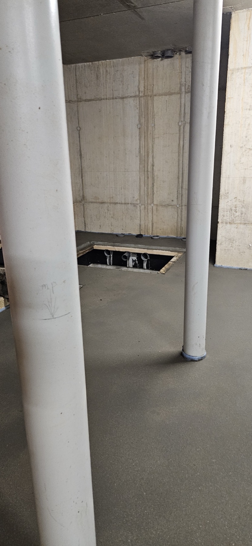 Afgewerkte dekvloer rond witte kolommen in een nieuwbouwruimte